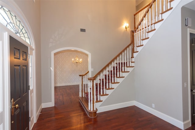 entryway with a towering ceiling, an inviting chandelier, and dark hardwood / wood-style flooring