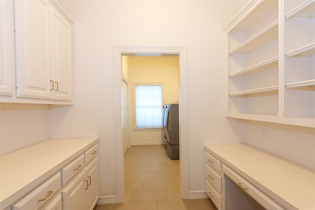 kitchen featuring light tile patterned flooring, washer / dryer, and white cabinets