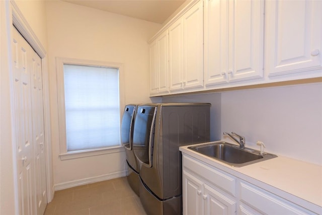 washroom with washing machine and clothes dryer, a sink, light tile patterned flooring, baseboards, and cabinet space
