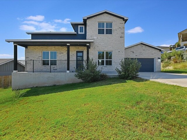 traditional-style home featuring covered porch, a garage, a front lawn, concrete driveway, and stone siding