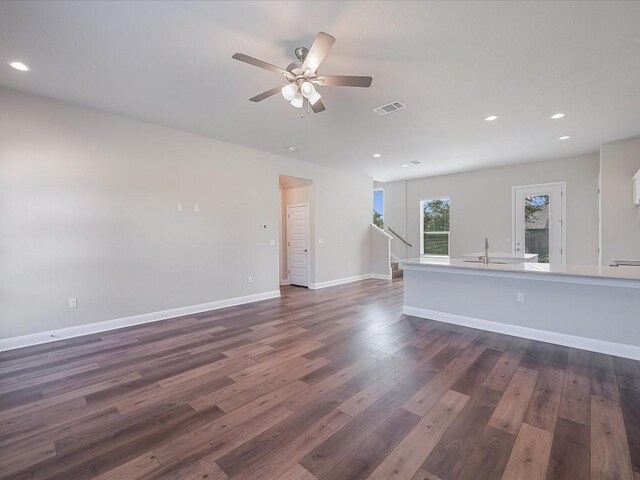 unfurnished living room with recessed lighting, a ceiling fan, dark wood finished floors, and visible vents