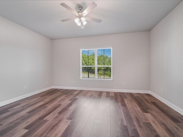 unfurnished room with baseboards, a ceiling fan, and dark wood-style floors