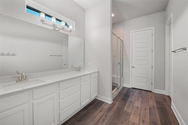 full bath with wood finished floors, baseboards, a sink, and a stall shower