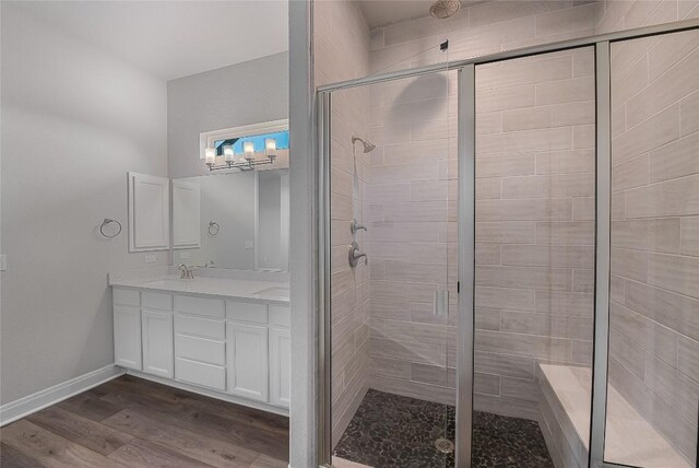 full bathroom with wood finished floors, baseboards, a stall shower, and vanity