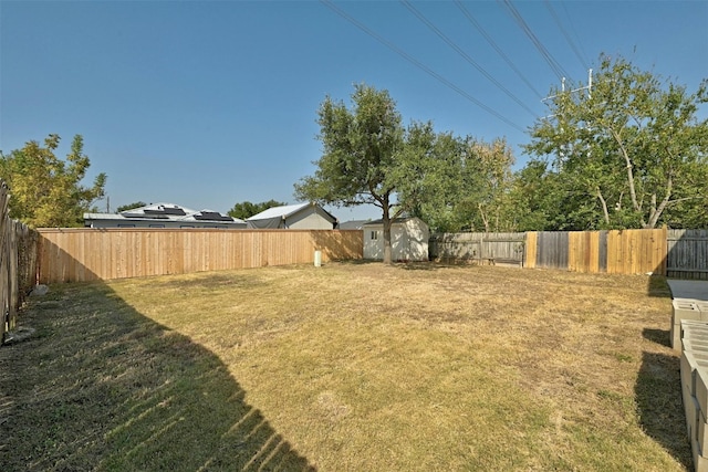 view of yard featuring a storage shed, an outdoor structure, and a fenced backyard