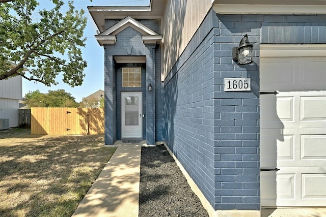 doorway to property featuring central air condition unit and a garage