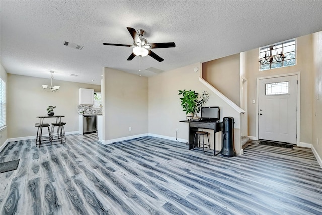 entrance foyer featuring visible vents, ceiling fan with notable chandelier, wood finished floors, stairway, and baseboards