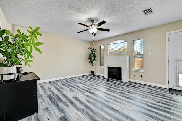 living room featuring visible vents, a brick fireplace, ceiling fan, baseboards, and wood finished floors