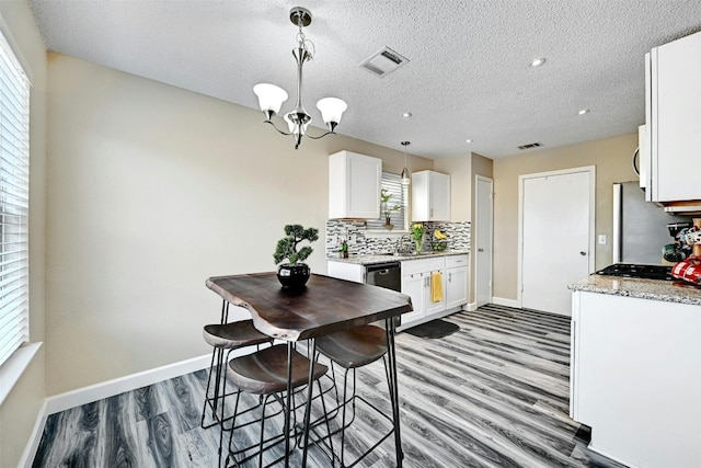 kitchen with white cabinetry, decorative backsplash, wood finished floors, and visible vents