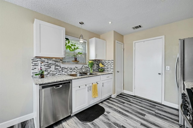 kitchen featuring a sink, backsplash, light wood-style floors, appliances with stainless steel finishes, and white cabinets