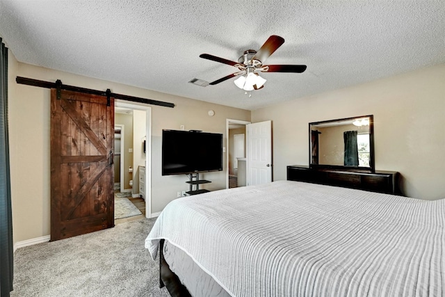 carpeted bedroom with a ceiling fan, baseboards, ensuite bath, a textured ceiling, and a barn door