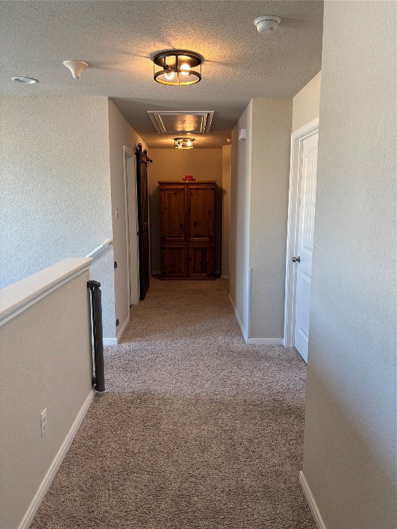 corridor featuring a textured ceiling and light colored carpet