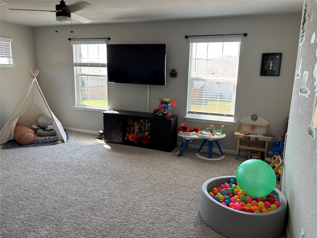 recreation room featuring ceiling fan, a textured ceiling, carpet, and a wealth of natural light