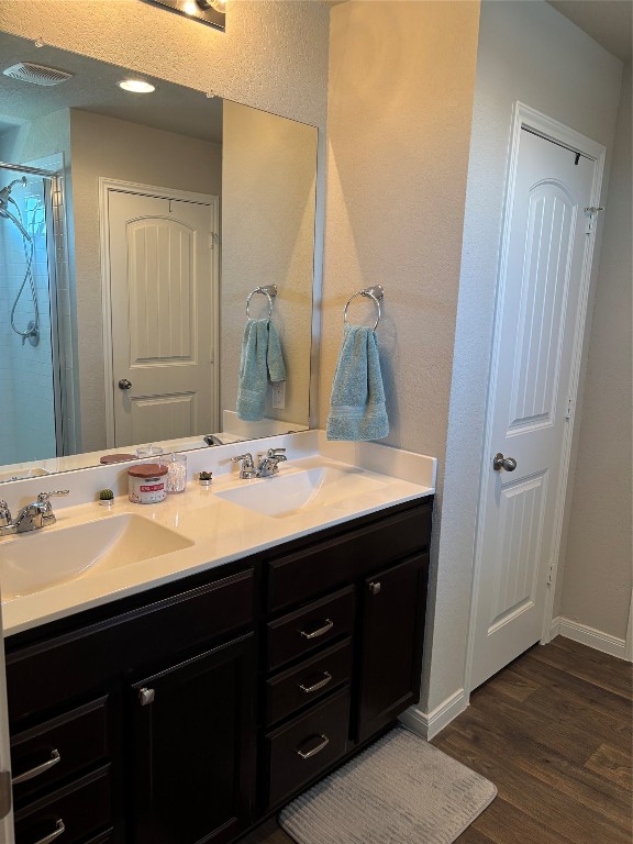 bathroom with vanity, a shower with shower door, and hardwood / wood-style floors