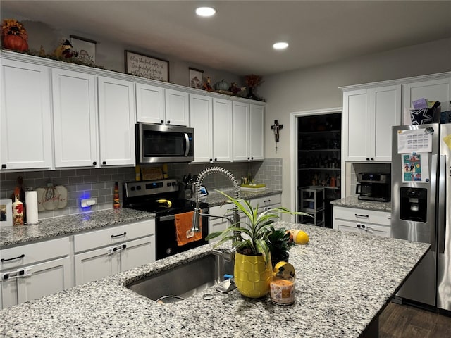 kitchen featuring dark wood-type flooring, tasteful backsplash, white cabinets, and appliances with stainless steel finishes