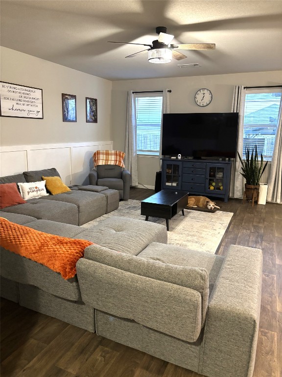 living room featuring dark wood-type flooring and ceiling fan