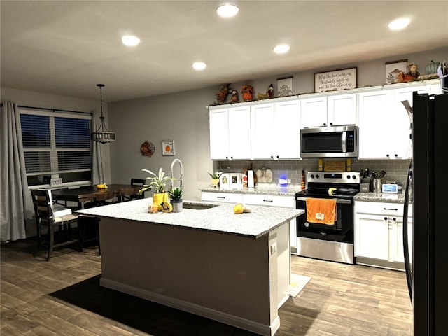 kitchen featuring appliances with stainless steel finishes, light wood-type flooring, white cabinetry, and a center island with sink