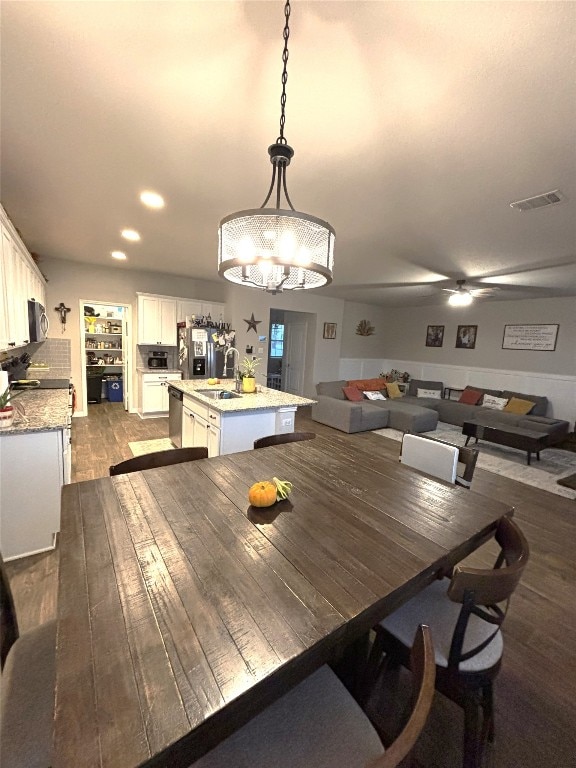 dining room featuring ceiling fan with notable chandelier, sink, and hardwood / wood-style floors