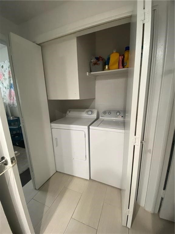 clothes washing area with light tile patterned floors and washer and dryer