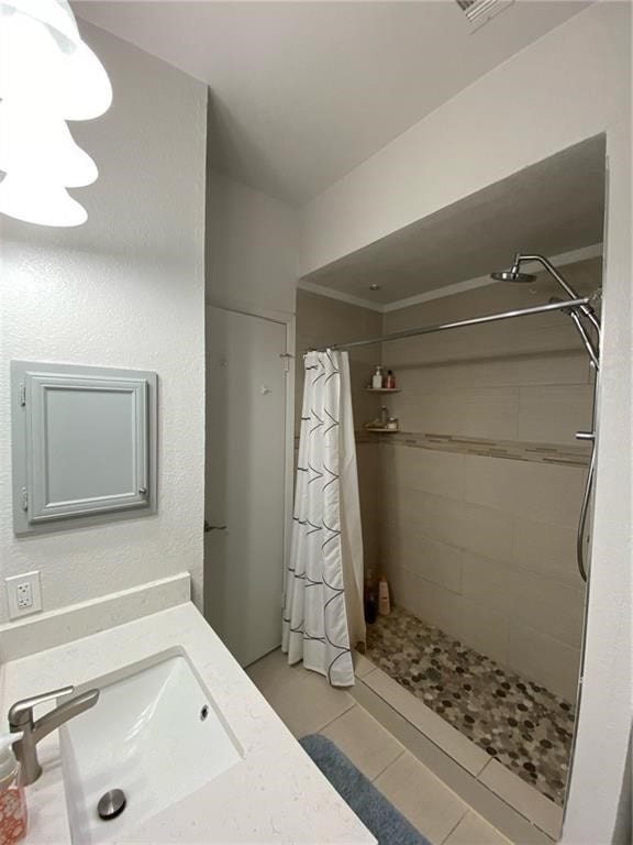 bathroom with walk in shower, sink, and tile patterned floors