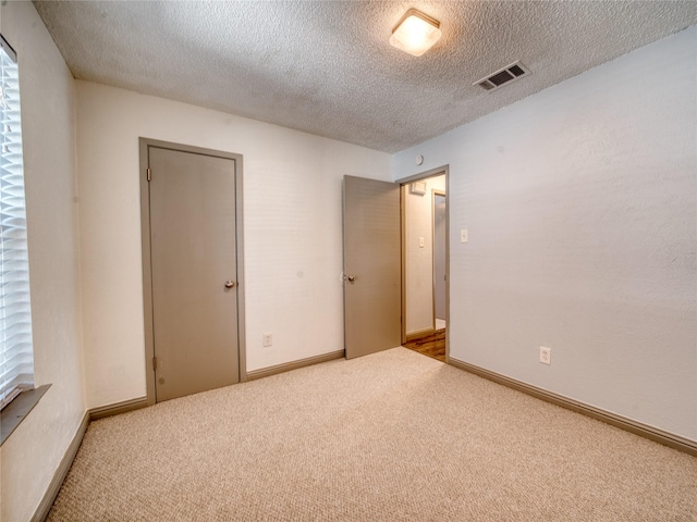 carpeted spare room featuring a textured ceiling