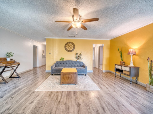 living room with a textured ceiling, light hardwood / wood-style flooring, ornamental molding, and ceiling fan