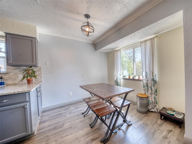 dining room with crown molding, light hardwood / wood-style flooring, and a textured ceiling