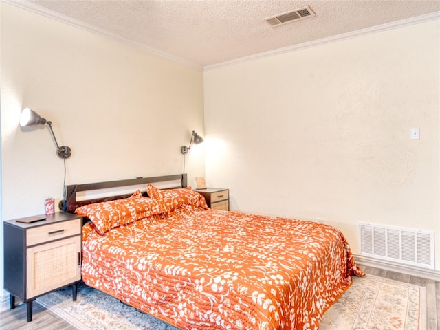 bedroom featuring ornamental molding, wood-type flooring, and a textured ceiling