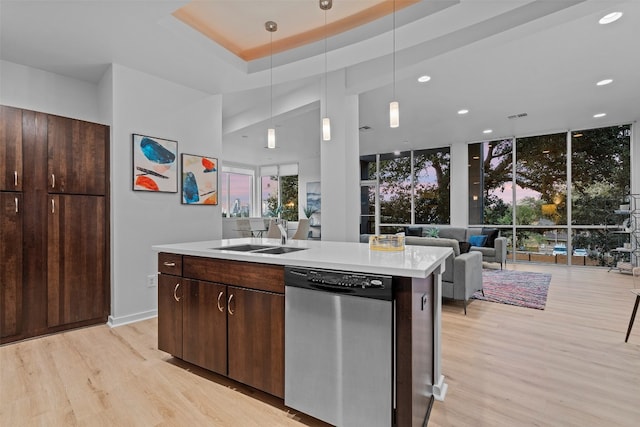 kitchen with dark brown cabinets, a center island with sink, dishwasher, light hardwood / wood-style floors, and sink