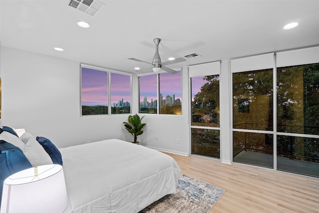 bedroom with expansive windows, light hardwood / wood-style flooring, and ceiling fan