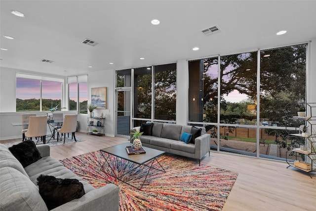 living room with a wall of windows and light hardwood / wood-style flooring