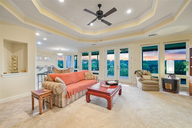 living room with light tile patterned flooring, ceiling fan, a raised ceiling, crown molding, and french doors