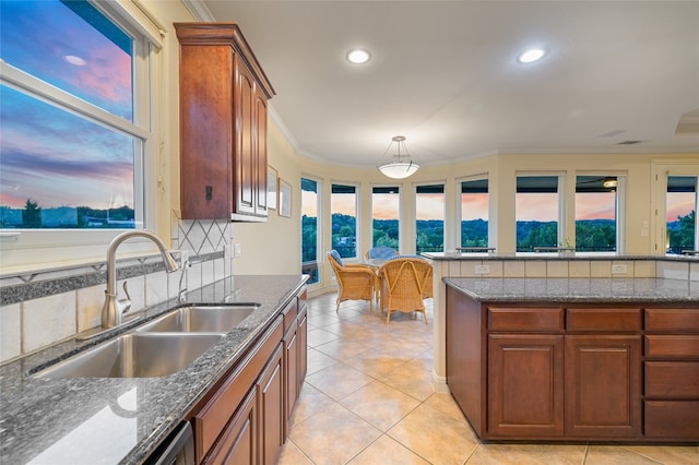 kitchen with dark stone counters, light tile patterned flooring, a sink, crown molding, and backsplash