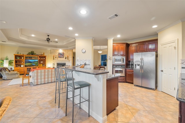 kitchen featuring dark stone countertops, visible vents, ceiling fan, stainless steel appliances, and a kitchen bar