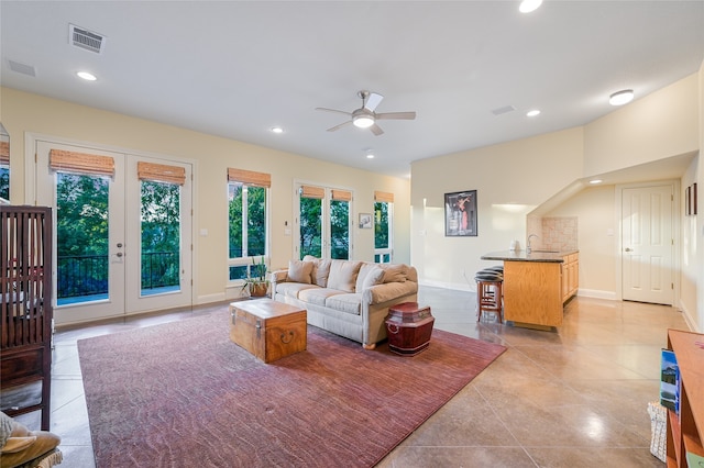 living room featuring sink, light tile patterned floors, ceiling fan, and french doors