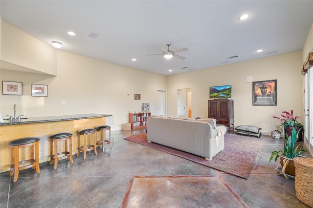 living room featuring ceiling fan and wet bar