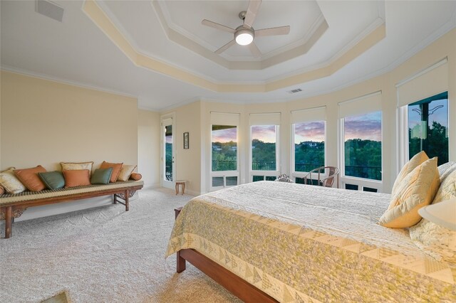 carpeted bedroom with ceiling fan, ornamental molding, and a raised ceiling