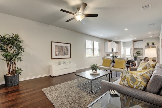 living room featuring ceiling fan and dark wood-type flooring