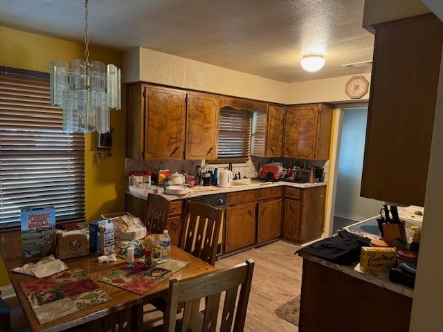 kitchen featuring an inviting chandelier, hanging light fixtures, light hardwood / wood-style flooring, and a textured ceiling