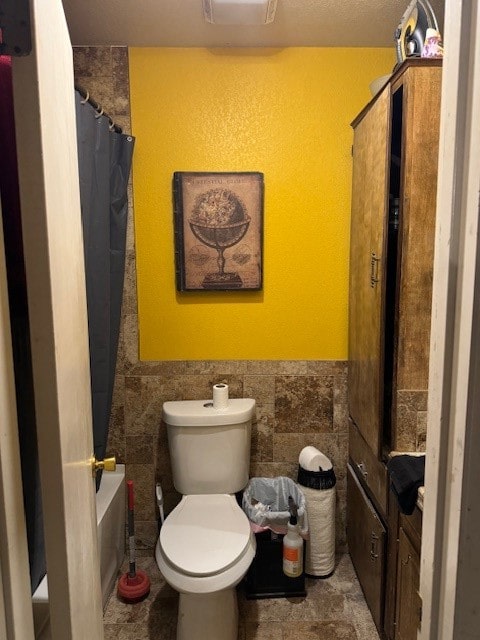 bathroom with shower / tub combo with curtain, tile walls, and toilet