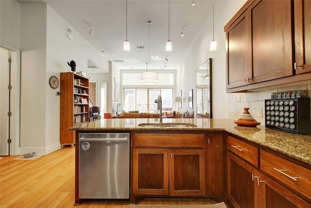 kitchen featuring stainless steel dishwasher, light wood-type flooring, sink, pendant lighting, and light stone counters