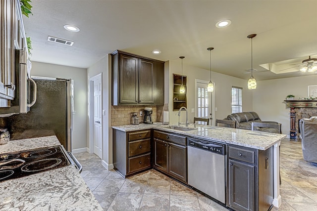 kitchen featuring light stone countertops, sink, hanging light fixtures, appliances with stainless steel finishes, and backsplash