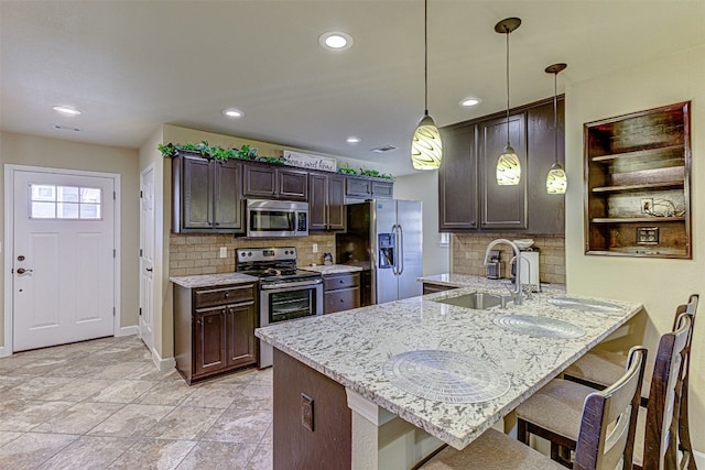 kitchen with pendant lighting, dark brown cabinetry, a kitchen breakfast bar, kitchen peninsula, and appliances with stainless steel finishes