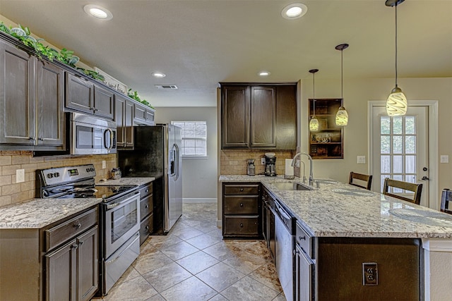 kitchen featuring stainless steel appliances, decorative light fixtures, sink, and dark brown cabinets