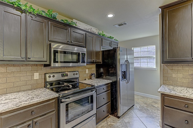 kitchen featuring tasteful backsplash, light stone countertops, appliances with stainless steel finishes, and dark brown cabinetry