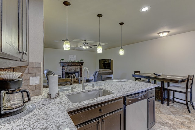 kitchen with ceiling fan, sink, stainless steel dishwasher, decorative light fixtures, and light stone countertops