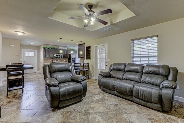 living room featuring a raised ceiling and ceiling fan