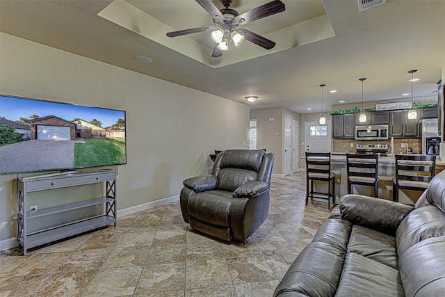 living room featuring ceiling fan and a tray ceiling