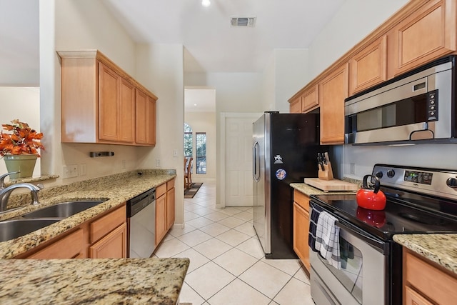 kitchen featuring light tile patterned flooring, light stone countertops, appliances with stainless steel finishes, and sink