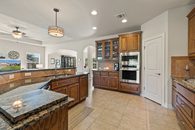 kitchen with stainless steel appliances, sink, backsplash, and decorative light fixtures